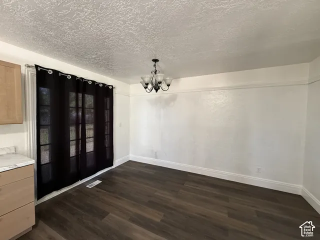 Wood-finish flooring with white trim, a decorative ceiling, and a multi-light chandelier