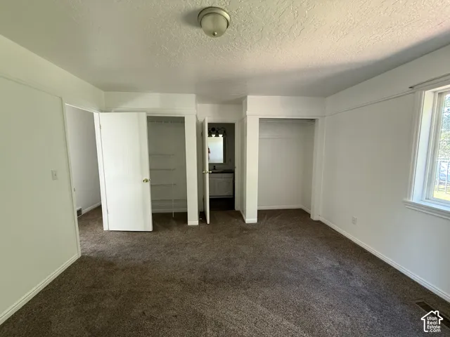 Carpeted flooring, white painted walls, a window with white trim, and a ceiling-mounted light fixture