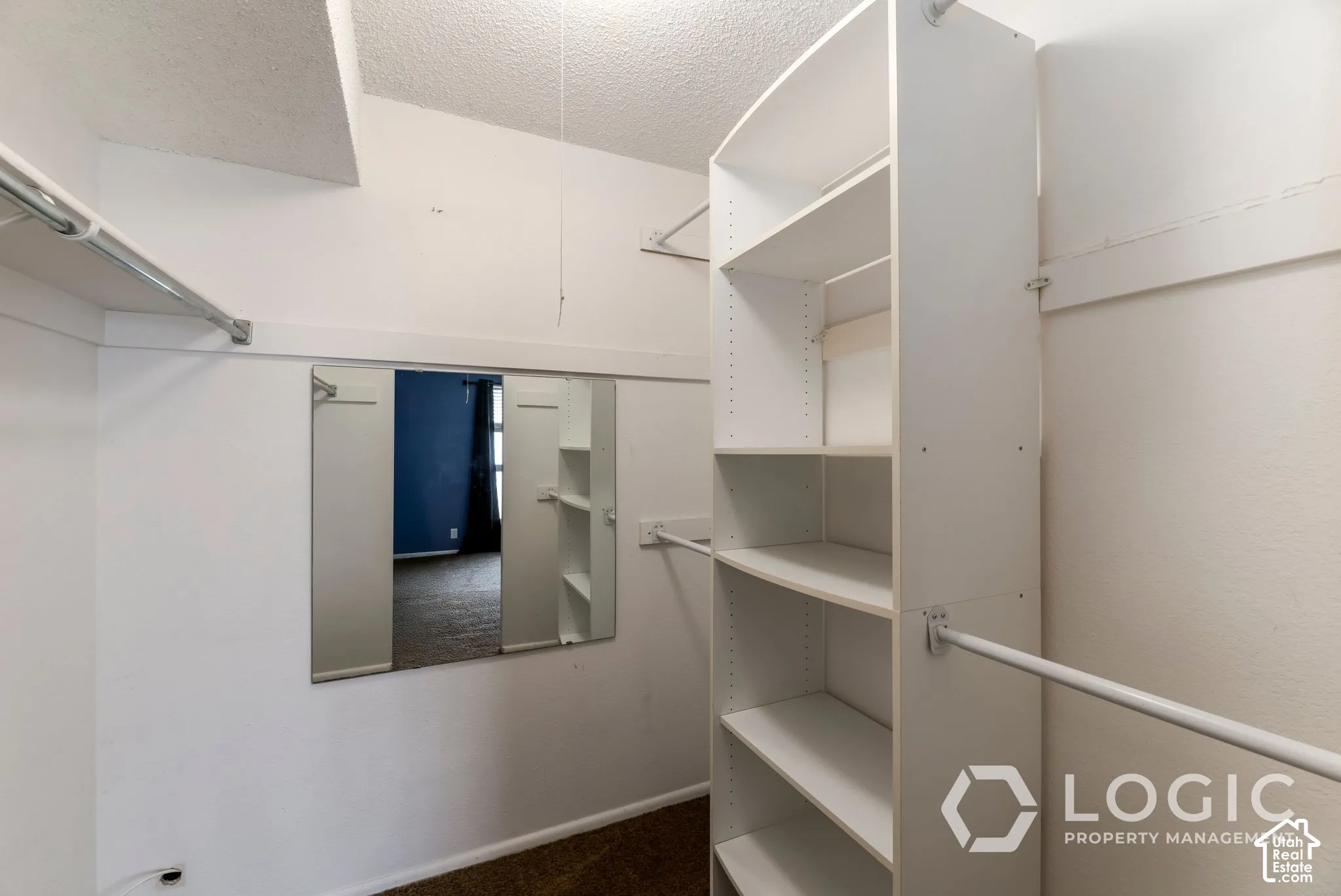 White built-in shelving, chrome hanging rods, and a large wall-mounted mirror