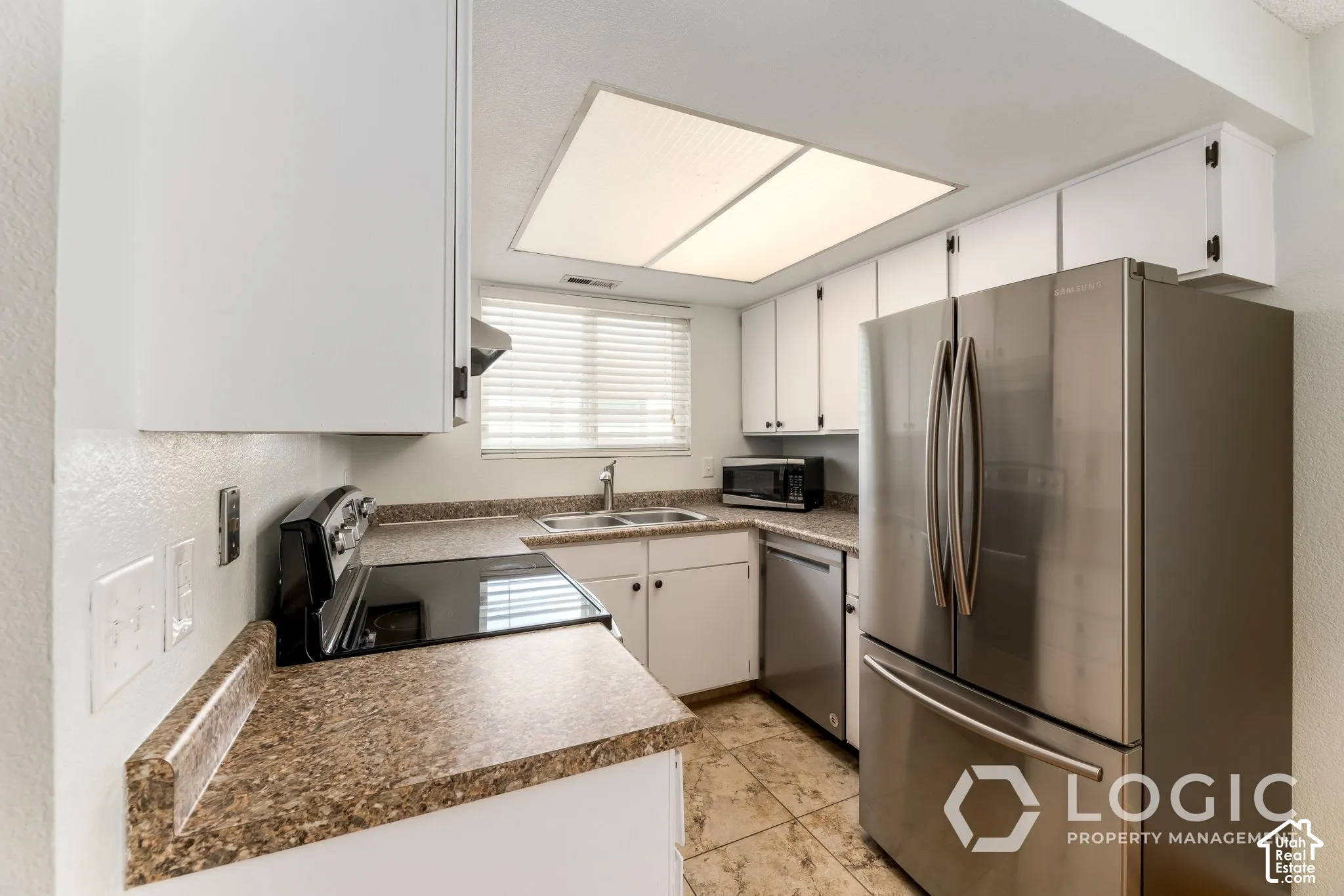 Kitchen featuring white cabinetry, stone-finish countertops, stainless steel appliances, and tile flooring
