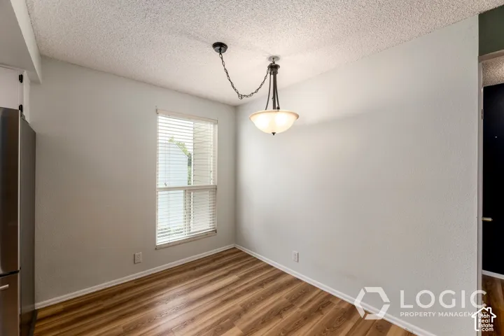 Wood-finish flooring, single window with blinds, overhead lighting fixture, and textured walls