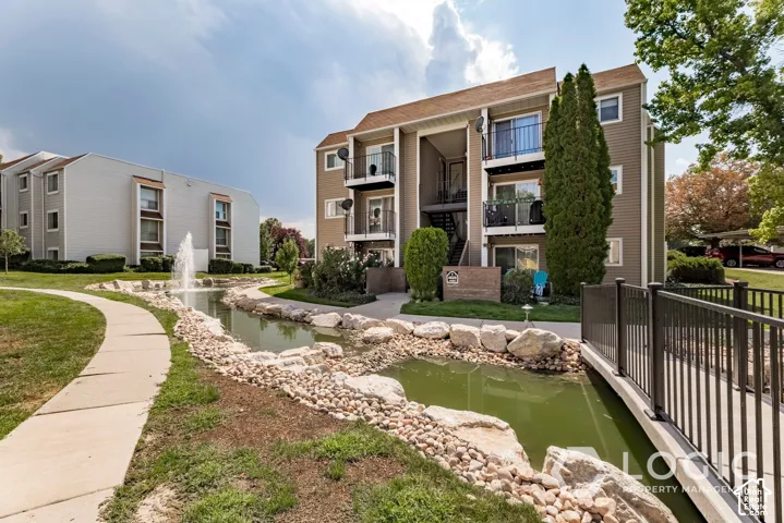 Manicured green spaces with a winding pathway, a decorative fountain, and a rock-lined water feature