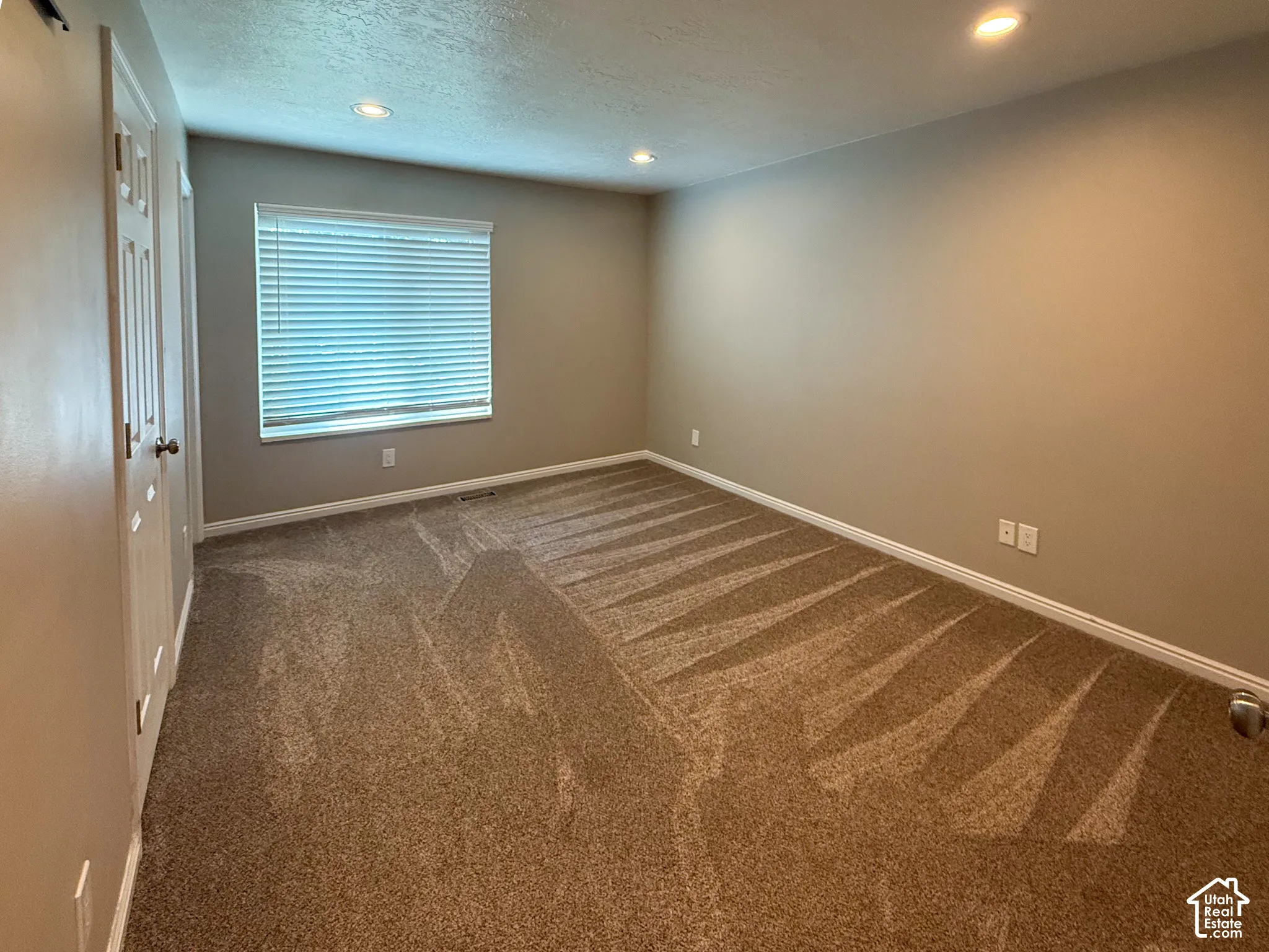Primary Bedroom 1 - Recessed lighting, neutral wall tones, window with horizontal blinds, textured carpet, and white trim