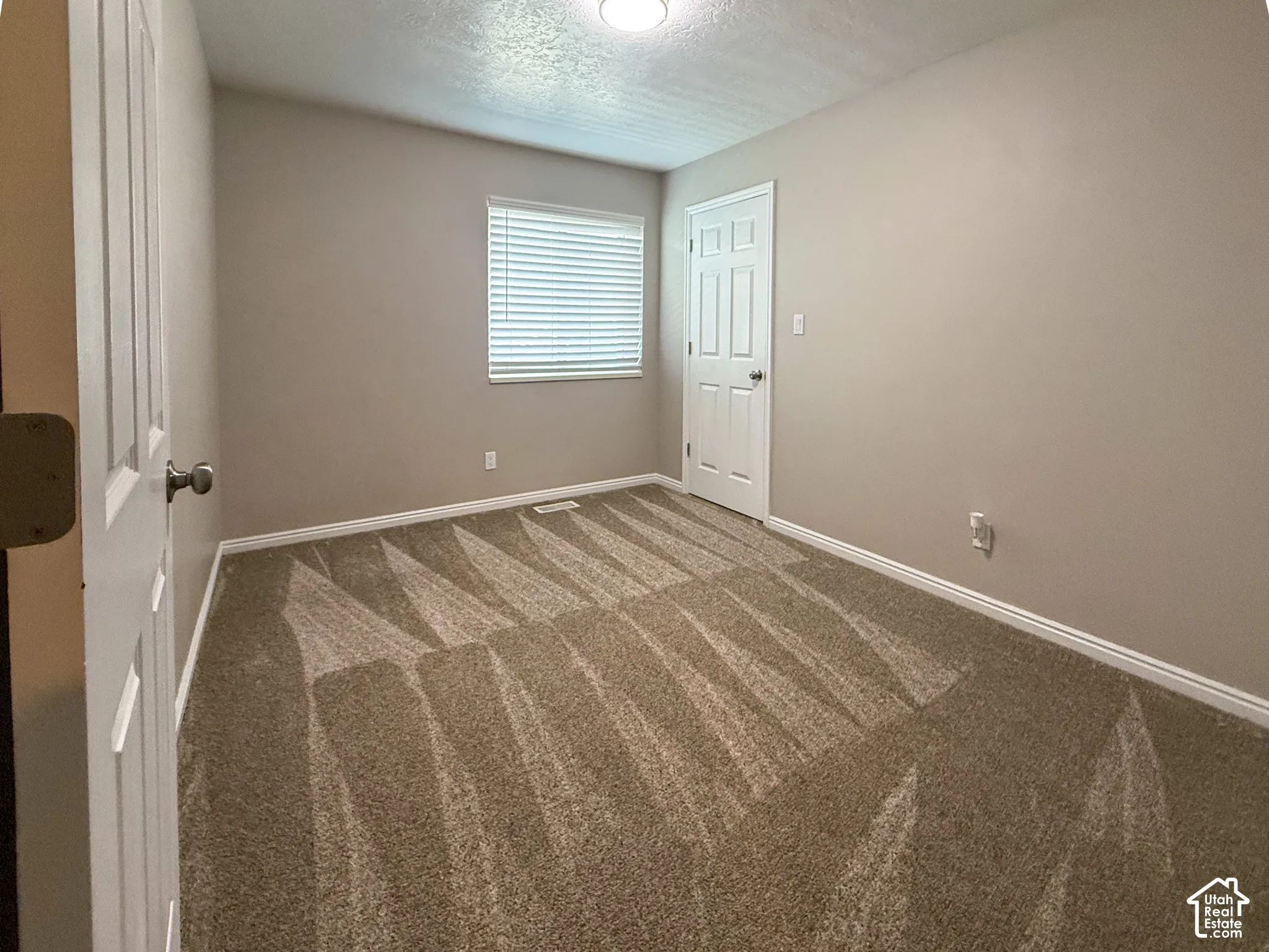 Bedroom 3 - Neutral wall paint, white trim, textured carpet flooring, window with blinds, and white panel doors
