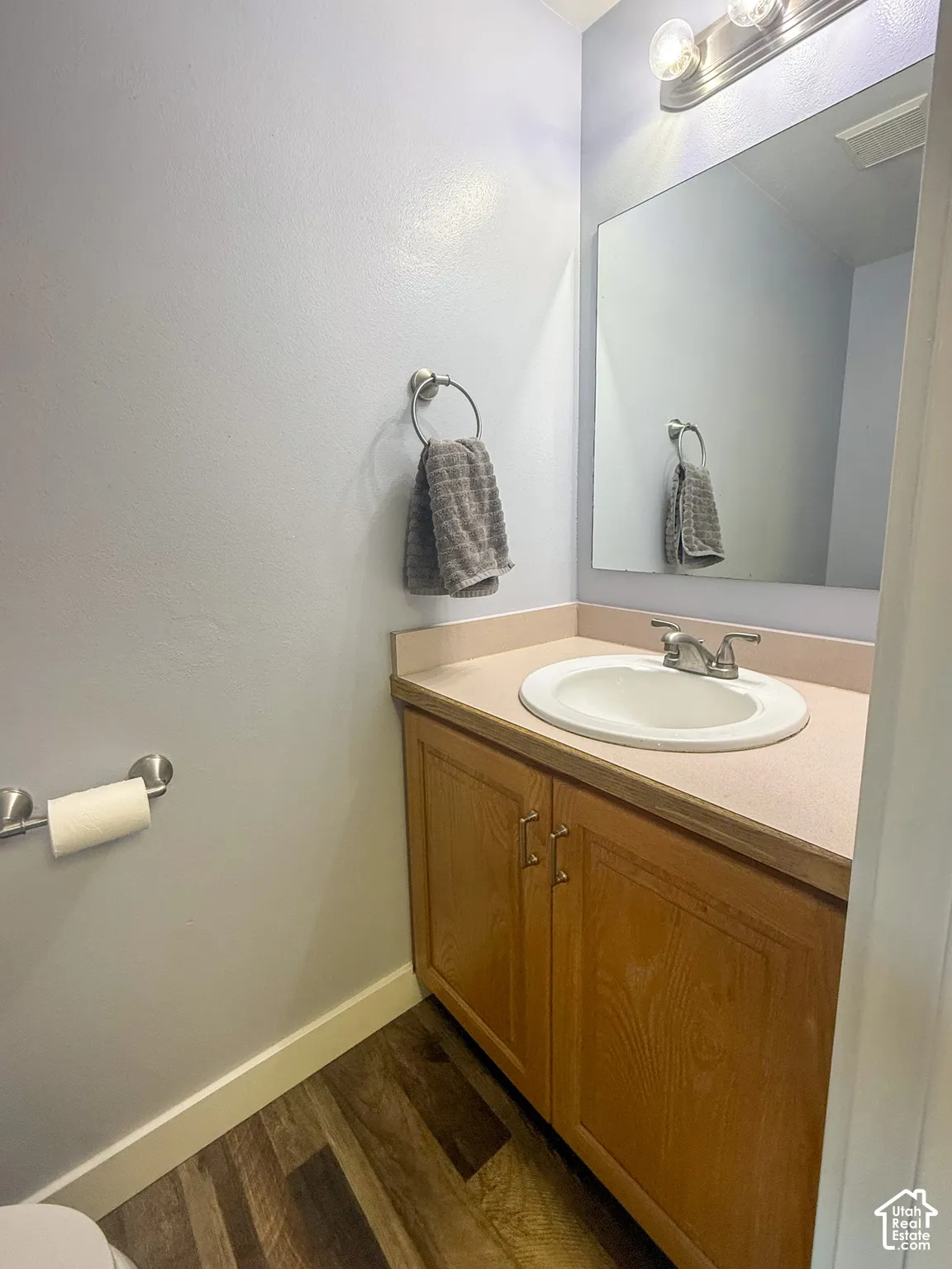Wood-finish flooring, wood cabinetry, and a countertop with integrated sink