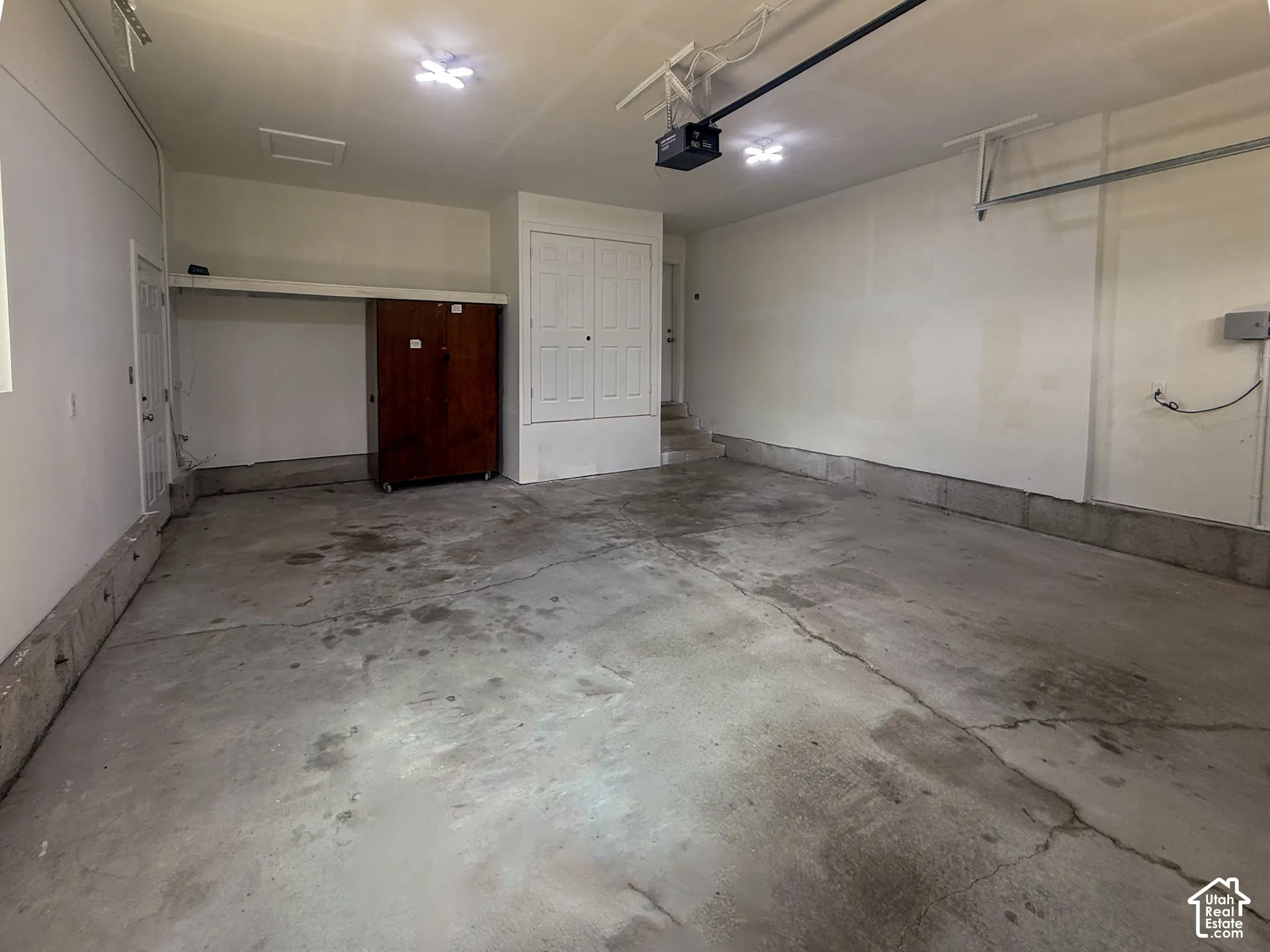 Attached garage with concrete flooring, built-in shelving, and overhead lighting