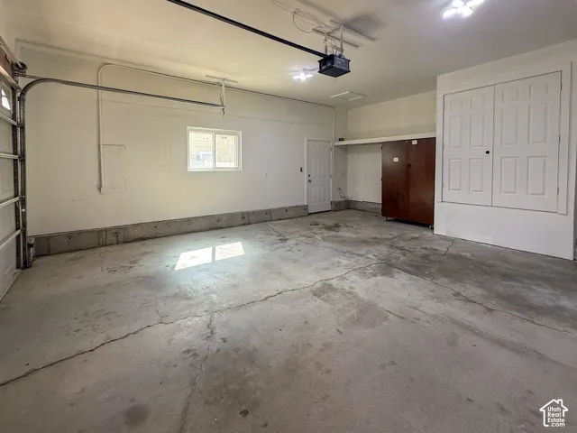 Spacious garage featuring a concrete floor, built-in storage cabinets, a window for natural light, and overhead lighting