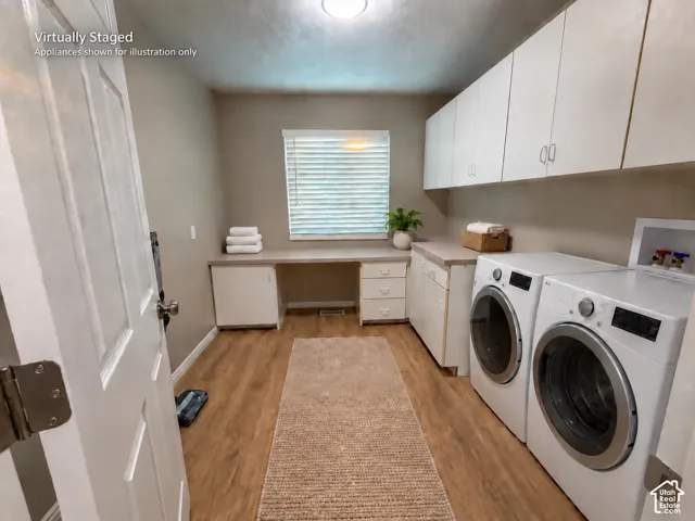 White upper cabinetry, wood-finish flooring, built-in desk, and a window with blinds