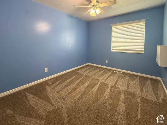 Bedroom 4 - Ceiling fan light fixture, window with blinds, and patterned carpet flooring
