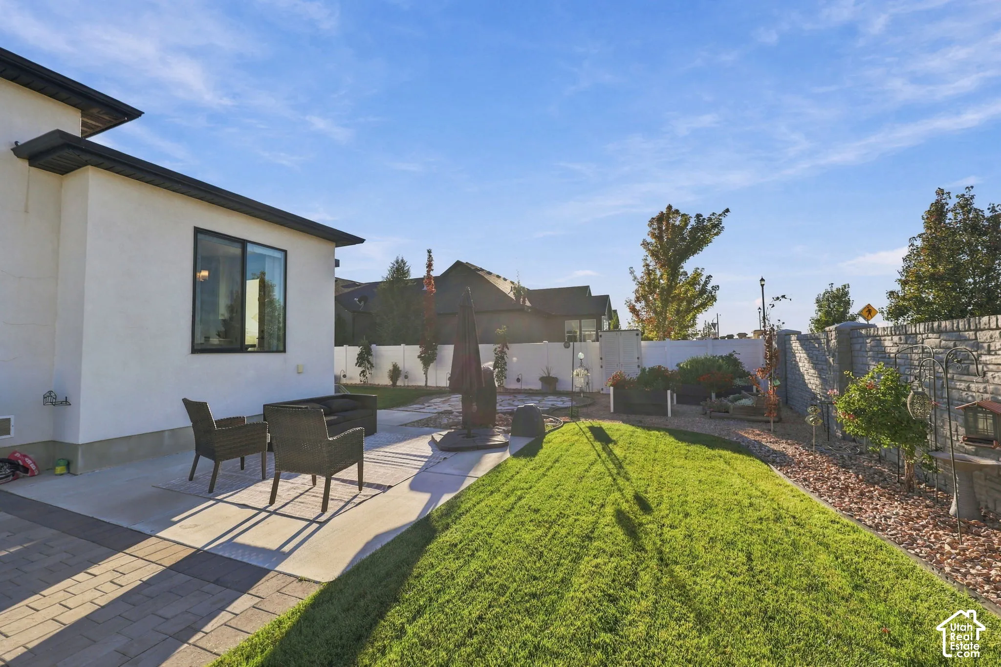 Private patio with paver and concrete surfaces, a manicured lawn, and a stone retaining wall
