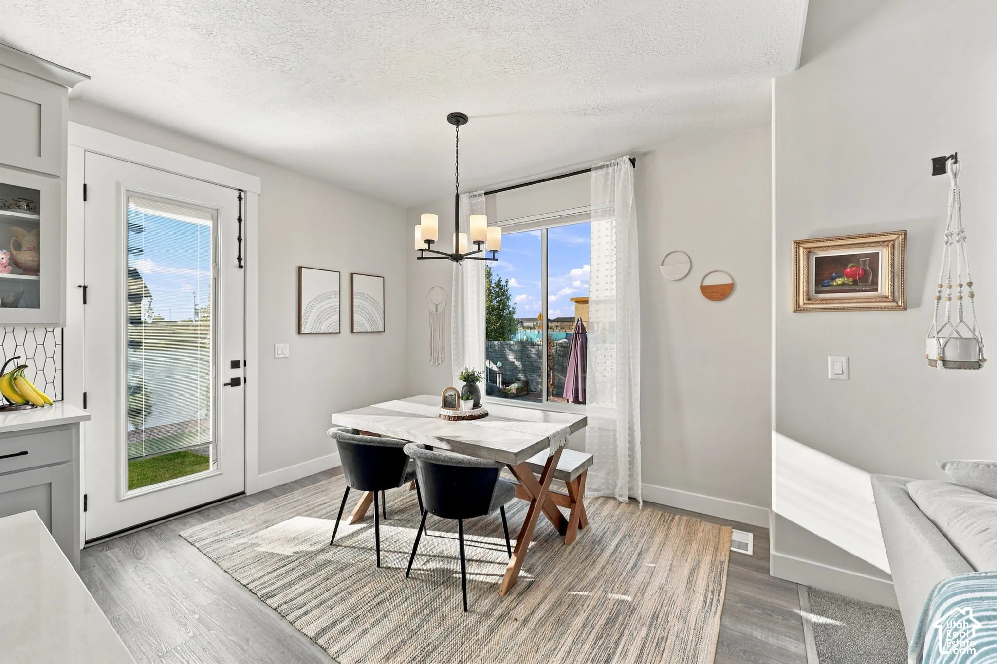 Dining area featuring wood-finish flooring, a contemporary chandelier, and a large window
