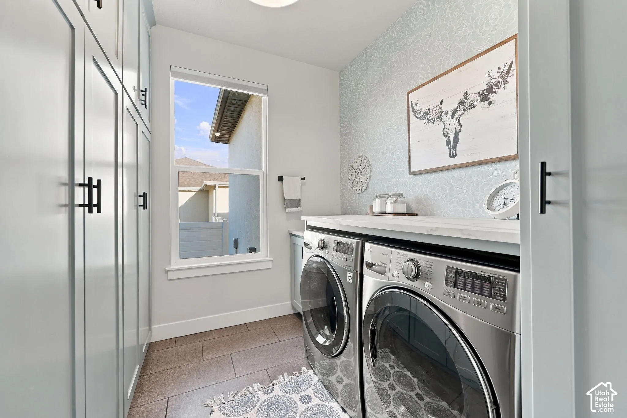 Laundry space featuring built-in cabinetry with matte black hardware, a single window, and a light-colored countertop