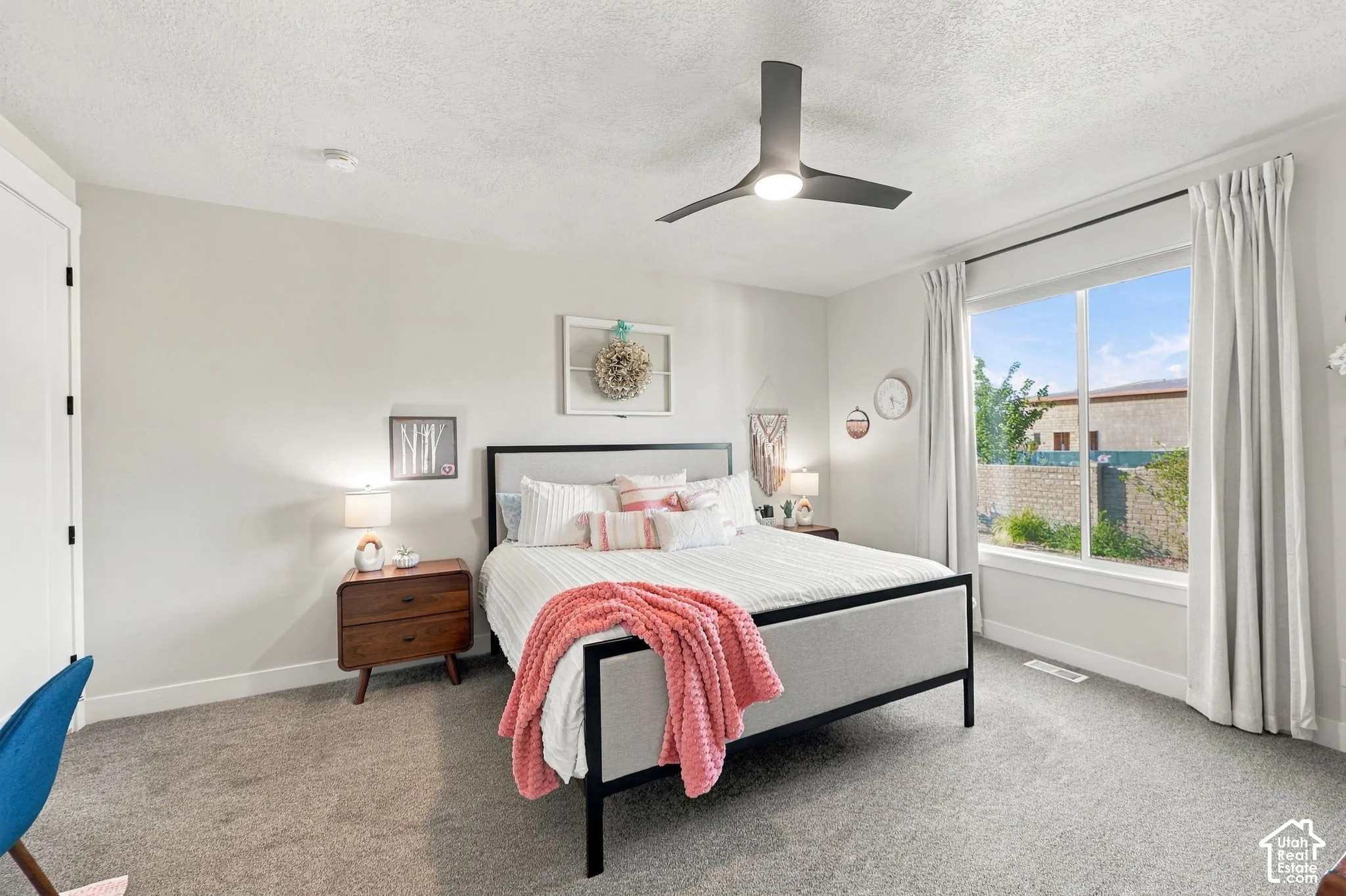 Spacious room featuring a large window, neutral wall tones, and plush carpeting
