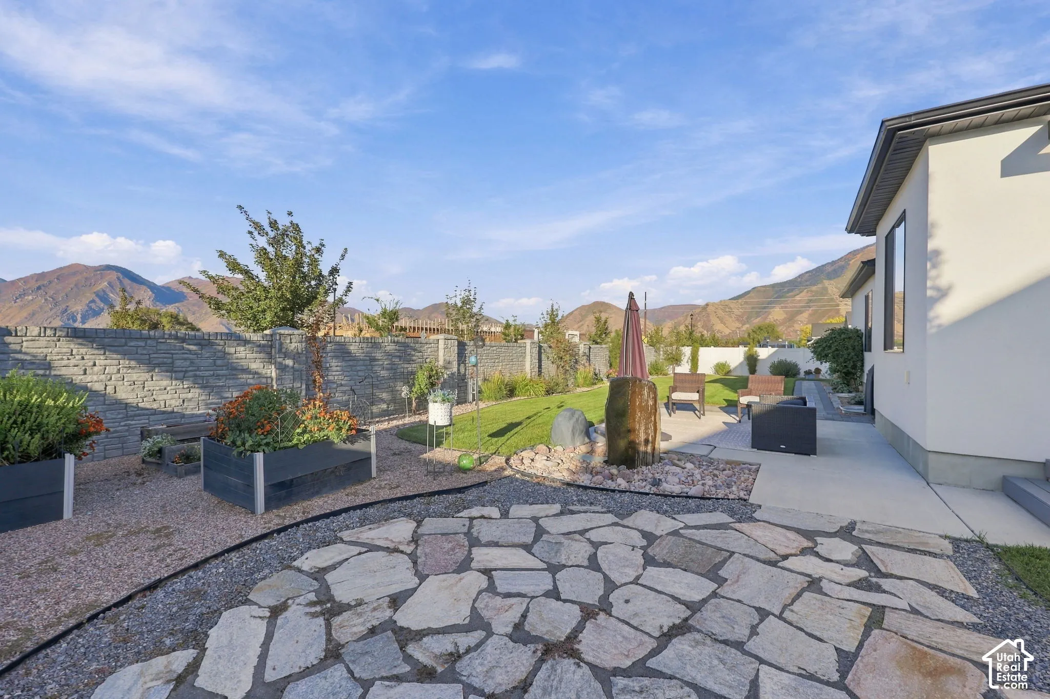 Flagstone patio with gravel border, manicured lawn, and raised garden beds