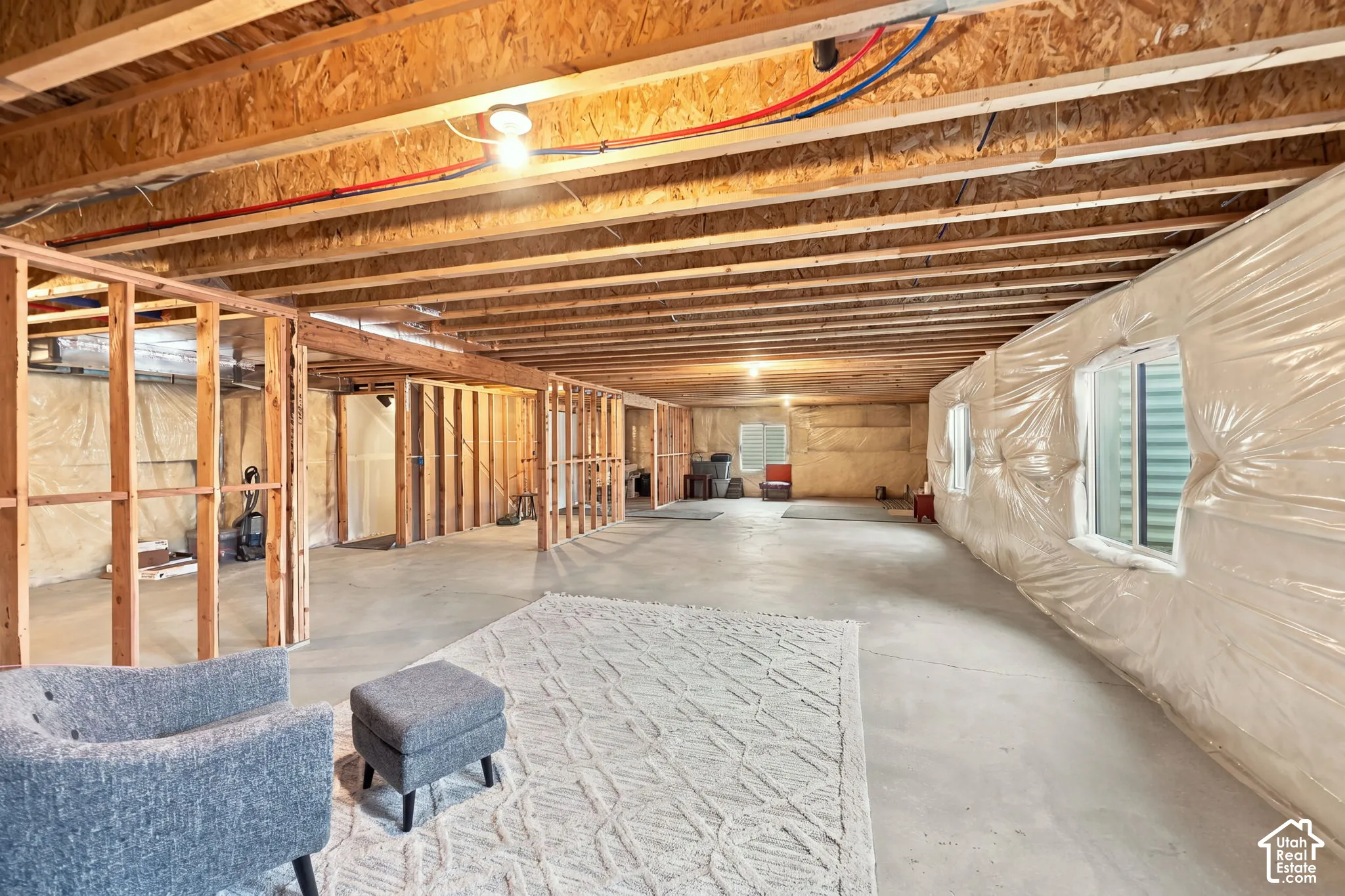 Expansive unfinished basement featuring exposed ceiling joists, concrete flooring, and multiple framed interior walls