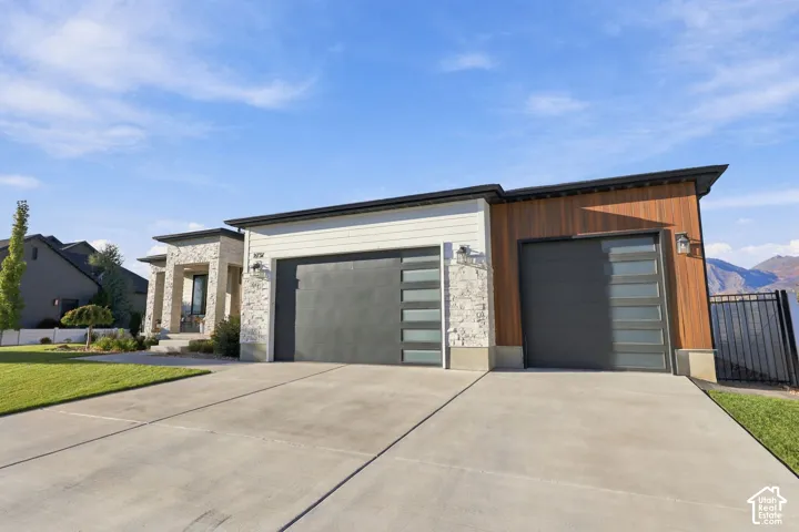 Contemporary exterior with wood paneling accents, stone facade, and a multi-car garage featuring modern frosted glass inserts