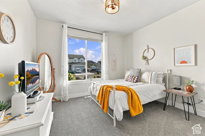 Carpeted room with a large window, a metal bed frame, a built-in light fixture, and white wall finishes