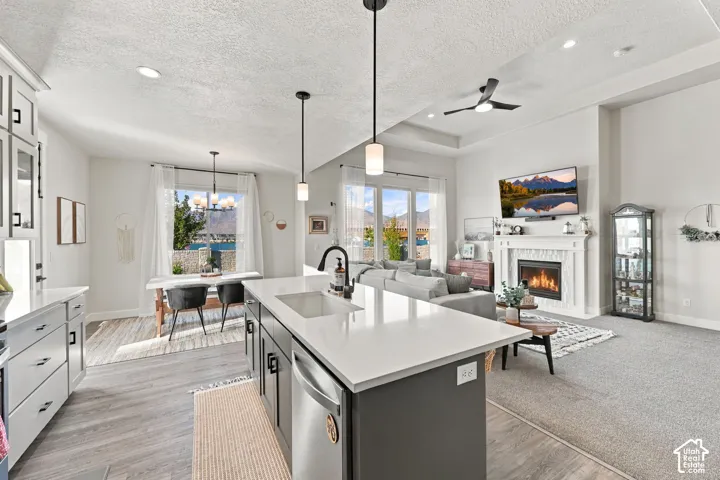Open-concept living space featuring a kitchen island with sink, a dining area with pendant lighting, and a living area with a built-in fireplace