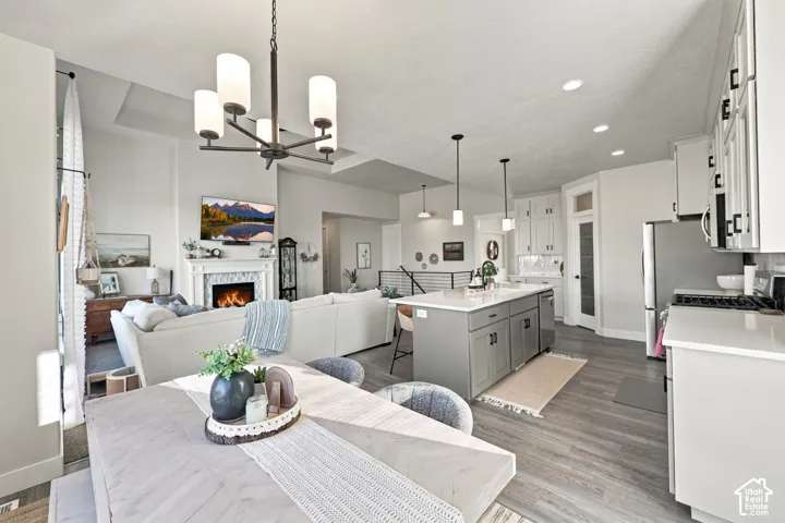 Open concept living area featuring a kitchen island with pendant lighting, a fireplace with a mantel, and wood-finish flooring