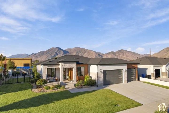 Contemporary exterior with stone facade accents, expansive concrete driveway, and dual garage doors