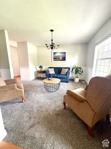 Recessed window, classic chandelier, wainscoting detail, light wall tones, and carpeted flooring