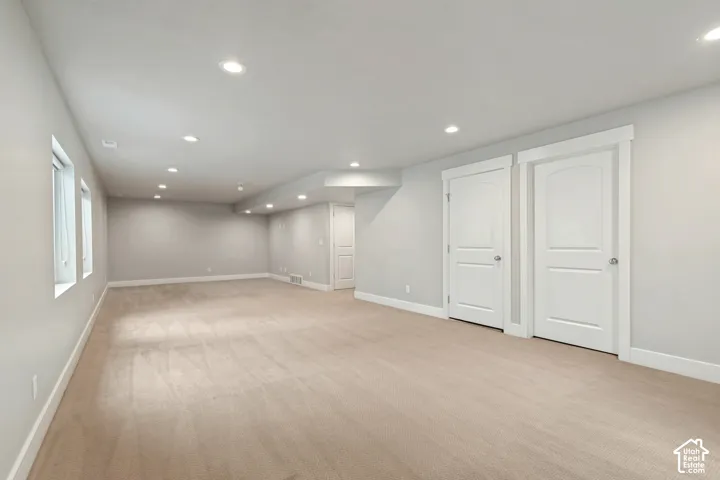 Recessed ceiling lighting, multiple windows, neutral wall tones, two-panel interior doors, and plush carpeting