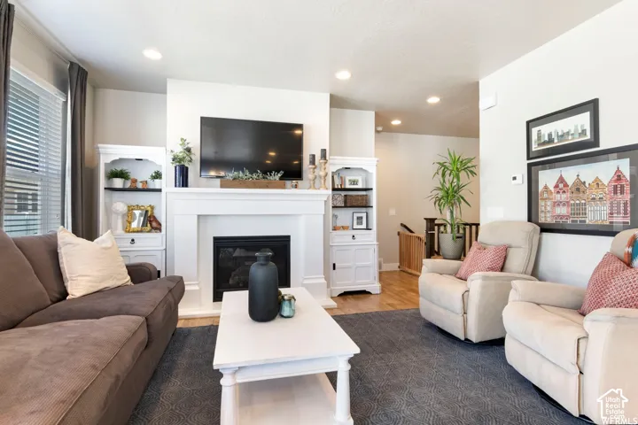 Recessed lighting illuminates this living area featuring a fireplace with a white mantel and built-in shelving