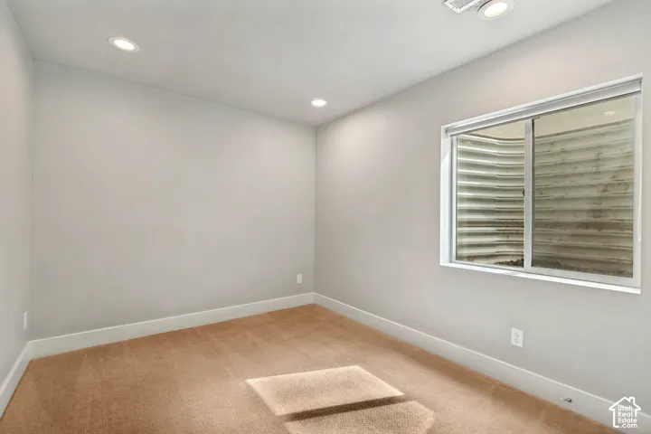 Recessed lighting, light-colored walls, broad window, and plush carpeting