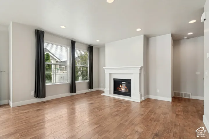 Wood-finish flooring, recessed lighting, and a fireplace with a classic mantel