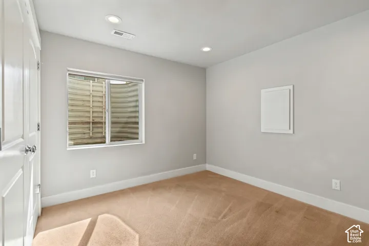 Neutral wall paint, recessed lighting, white trim, and light brown carpet create a versatile interior space