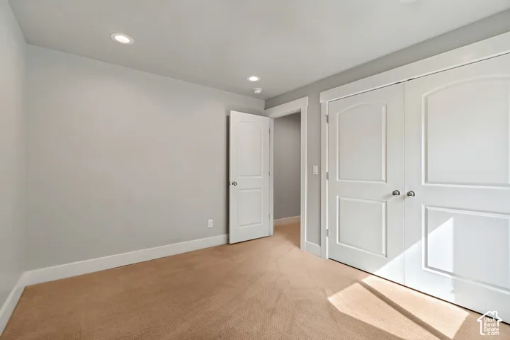 Recessed ceiling lighting, neutral-toned carpeting, white trim, and white paneled doors