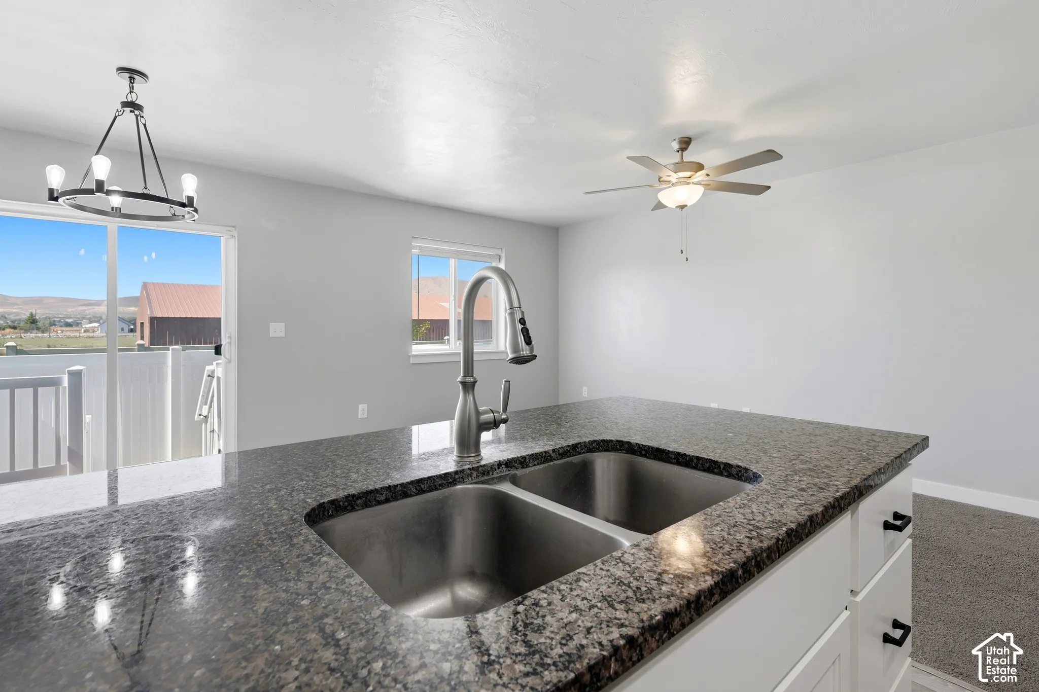 Kitchen island with a double basin stainless steel sink, a brushed nickel faucet, and a stone-finish countertop