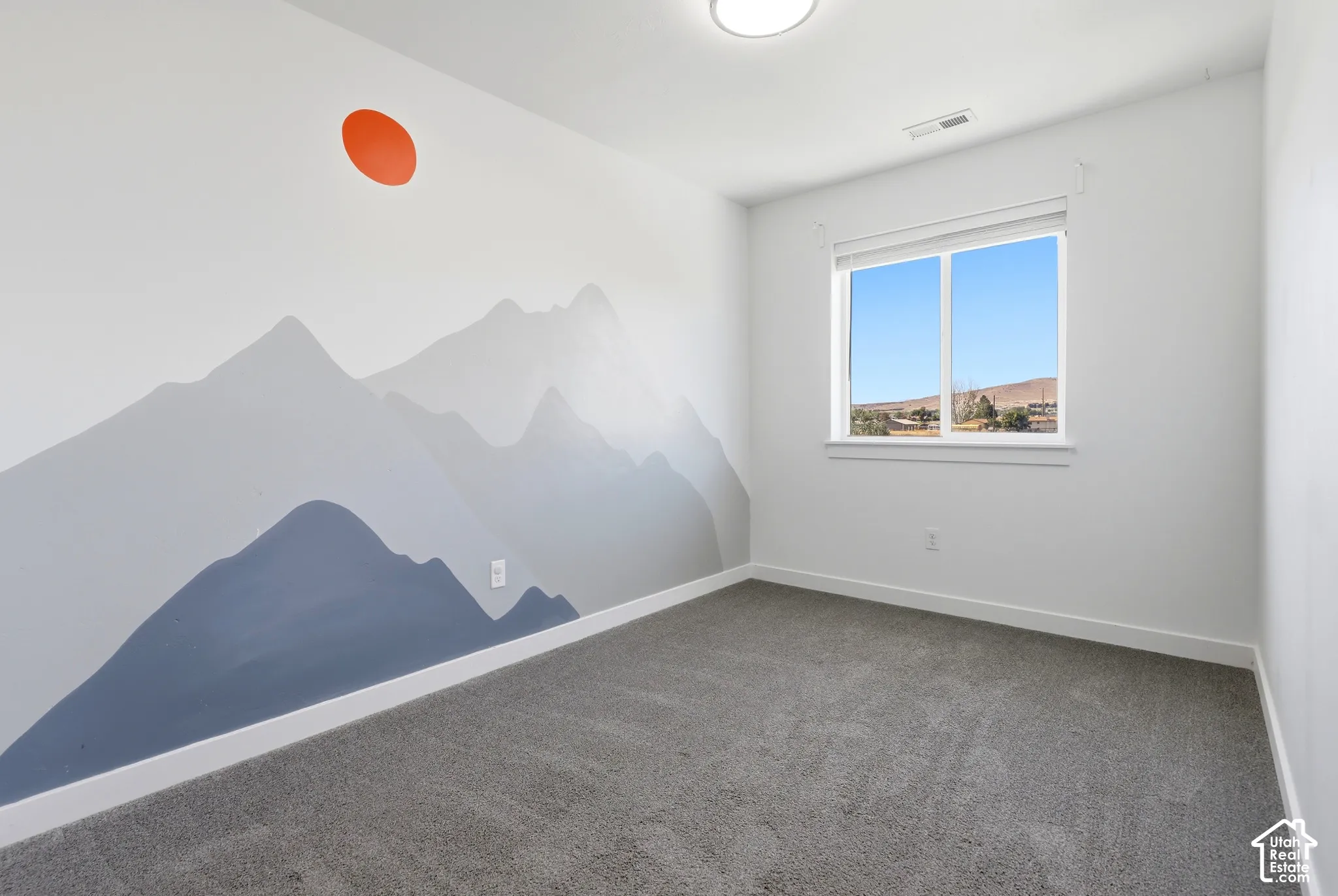 Wall with mountain motif mural and accent sun detail, featuring a window with a white frame, and gray carpet