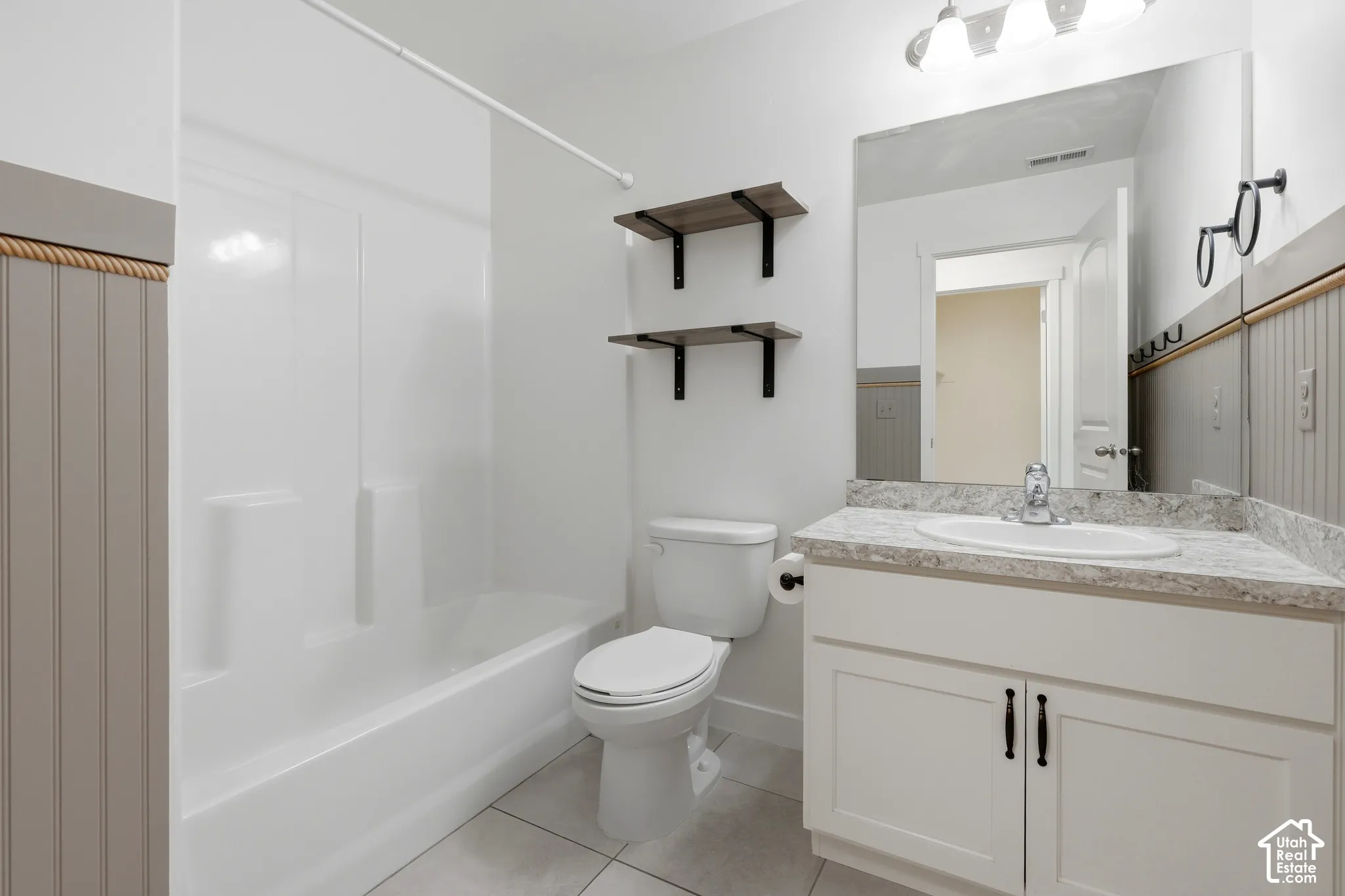 White vanity with cabinet storage, a drop-in sink, and a speckled countertop