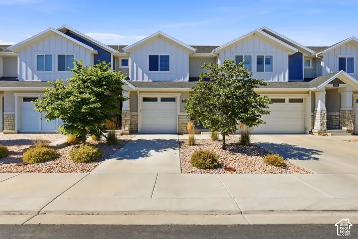 Contemporary townhome exterior featuring vertical siding, stone accents, attached garages, and xeriscape landscaping