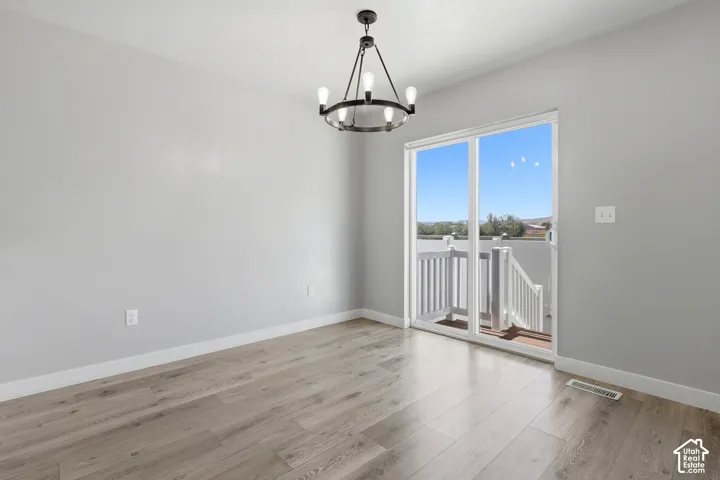 Wood-finish flooring, contemporary chandelier, sliding glass door, and a white deck railing system