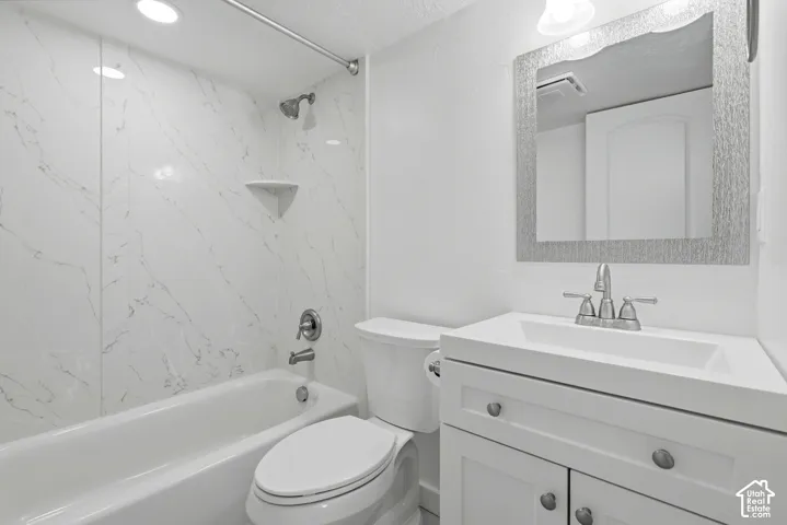 White vanity with an integrated sink and brushed nickel hardware, framed mirror, and a white bathtub with a tile surround