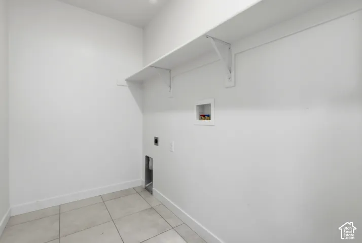 Utility area featuring tile flooring, a wall-mounted shelf, and appliance connections