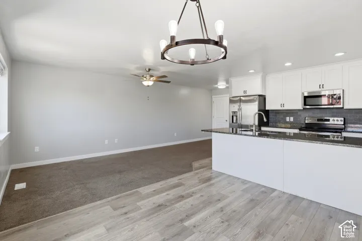 Kitchen featuring a dark stone countertop, white cabinetry, and stainless steel appliances