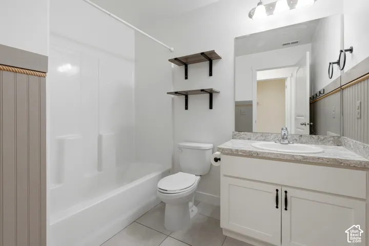 White vanity with cabinet storage, a drop-in sink, and a speckled countertop