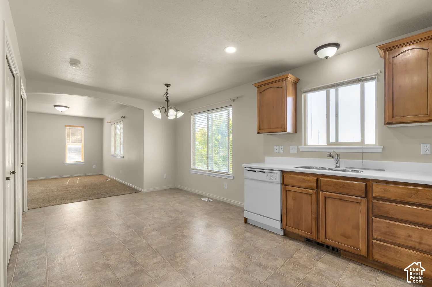 Kitchen area with wood cabinetry, white countertops, and a double-basin sink