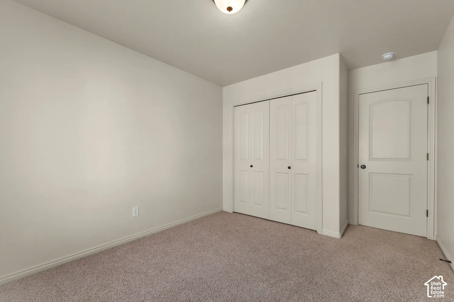 Neutral wall color, carpet flooring, a flush-mount ceiling light fixture, a bi-fold closet, and a paneled interior door