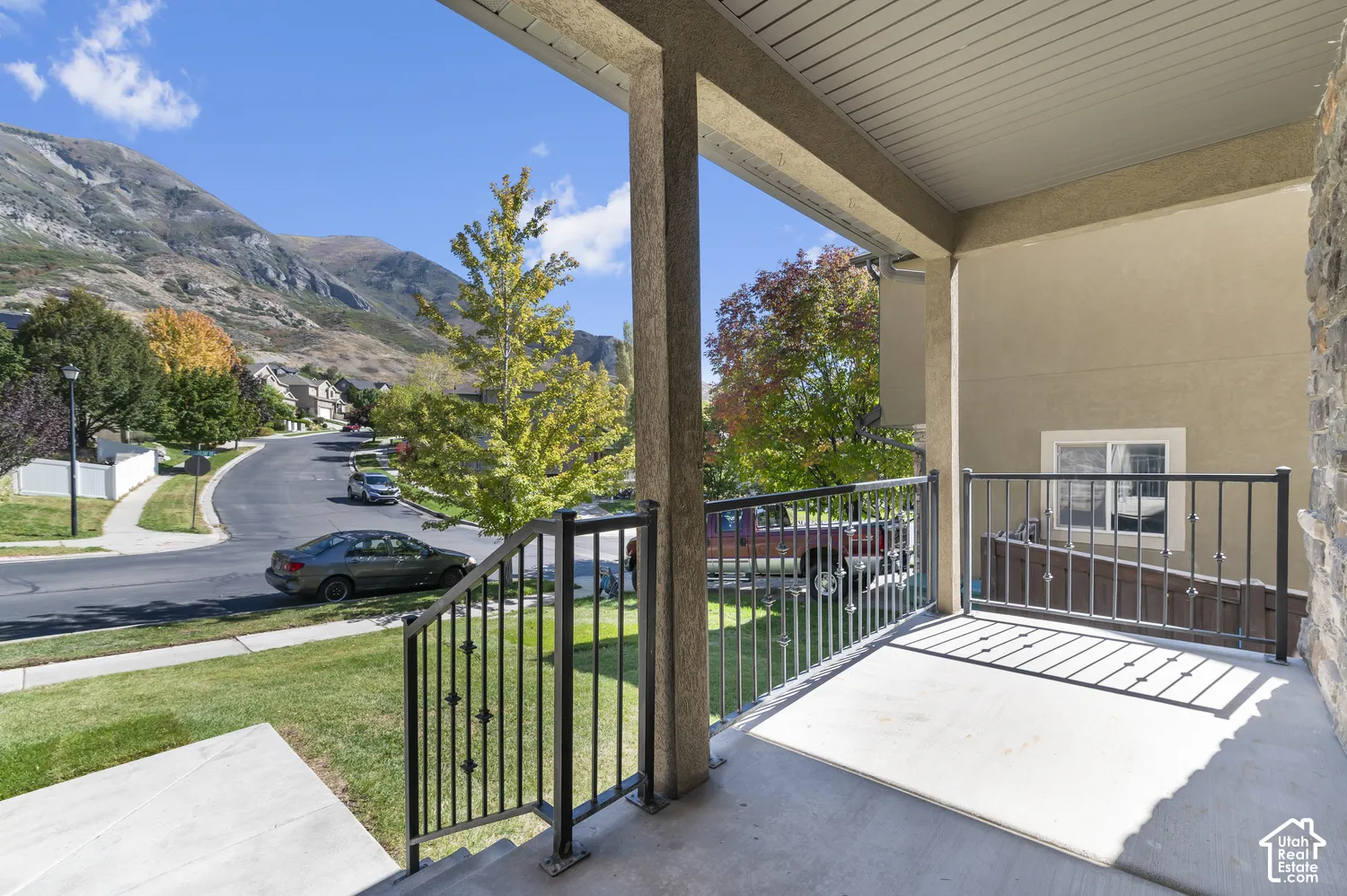 Covered porch featuring a concrete surface, black metal railing, and stucco siding