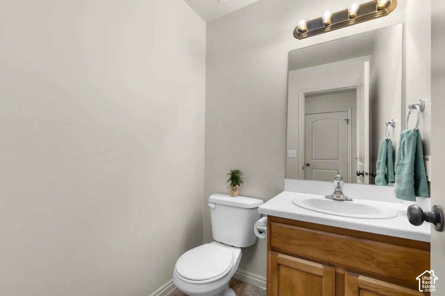 Half-Bath on Main-Vanity with wood-finish cabinetry, white countertop, and an oval sink