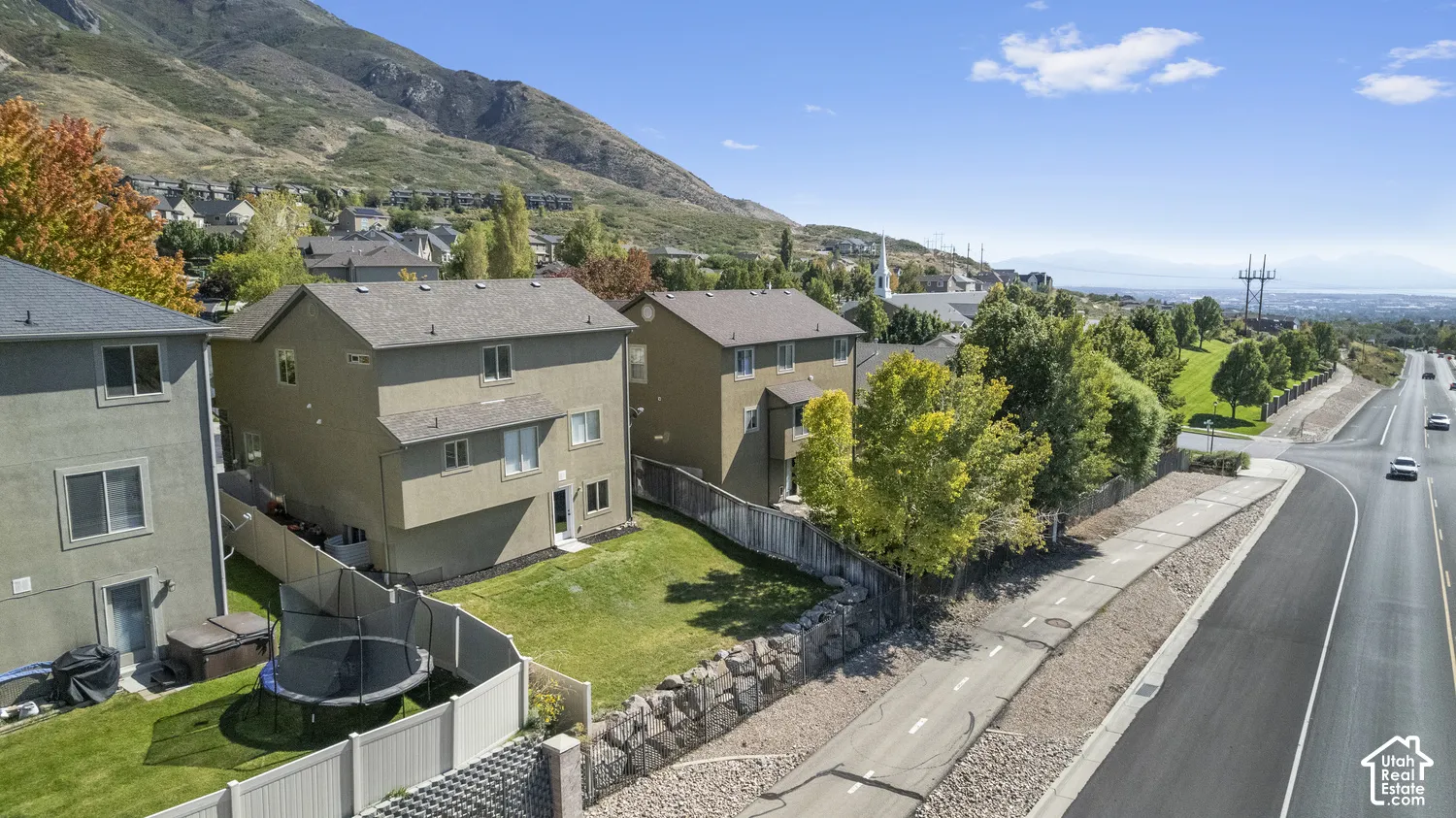 Mountain backdrop, residential area, adjacent road, paved pathway, green space