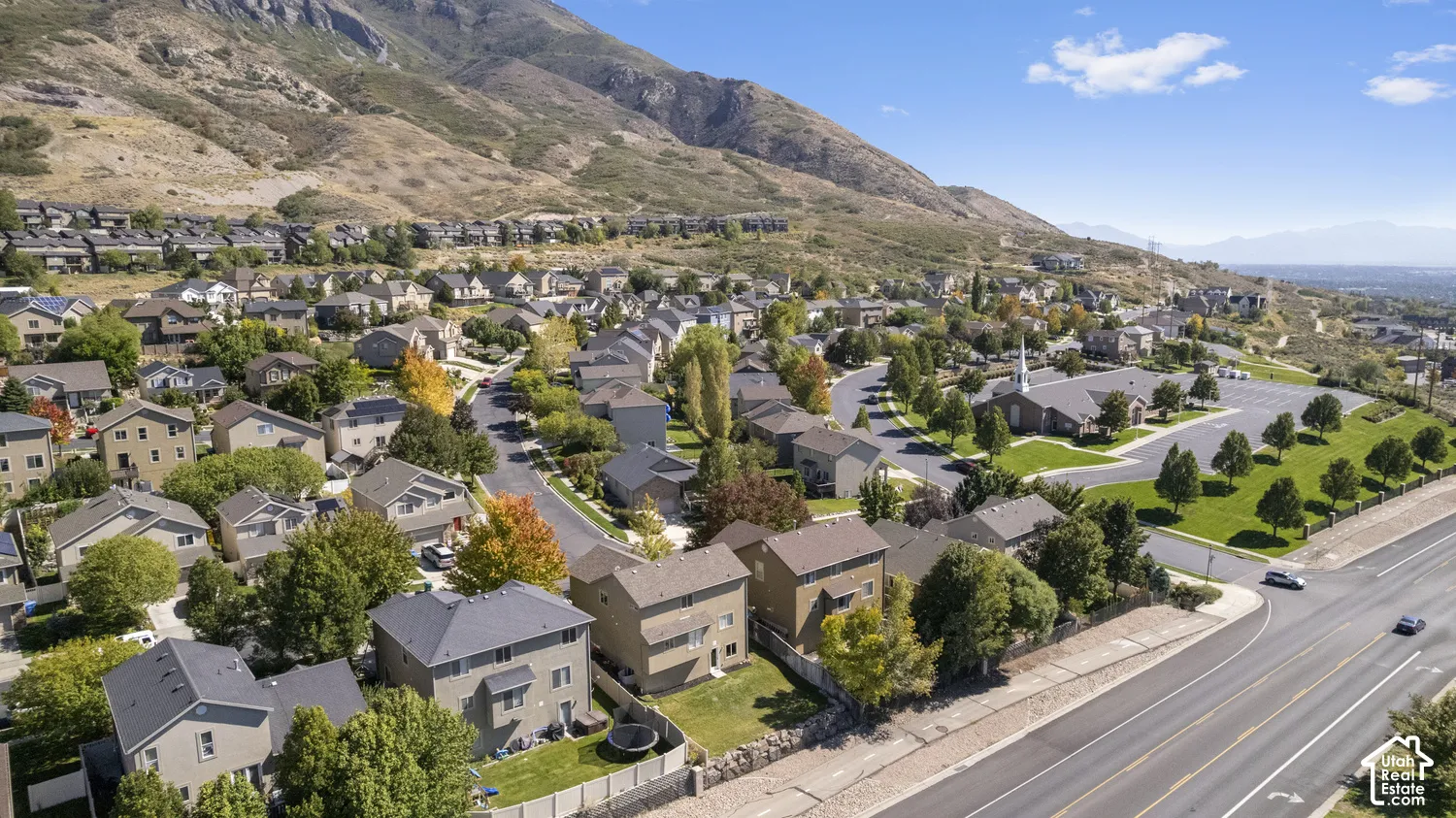 Residential area featuring multi-story homes, established trees, paved roads, and a mountainous backdrop