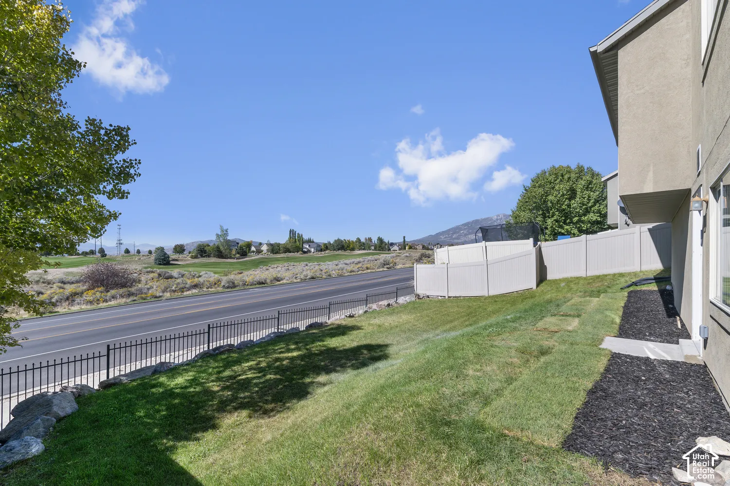 Sloped grassy yard with a black metal fence