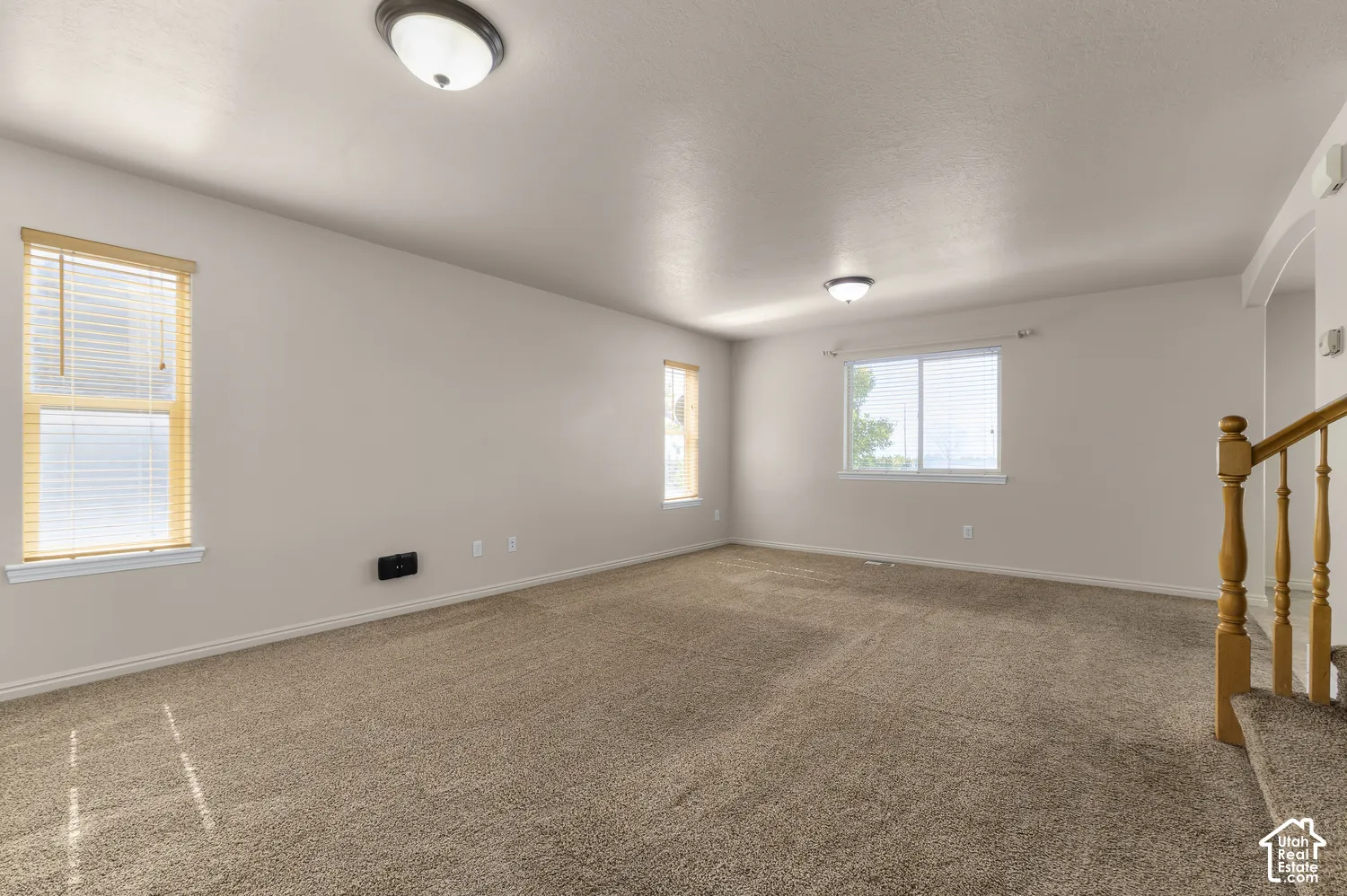 Expansive room featuring carpet flooring, multiple windows with blinds, and flush-mount ceiling lights