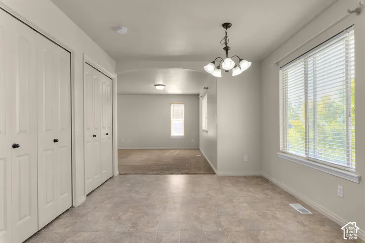 Neutral-toned interior with tile flooring, dual bi-fold closet doors, and a multi-bulb chandelier