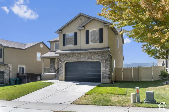 Two-story stucco and stone-faced residence with a two-car garage, covered entry, and a concrete driveway